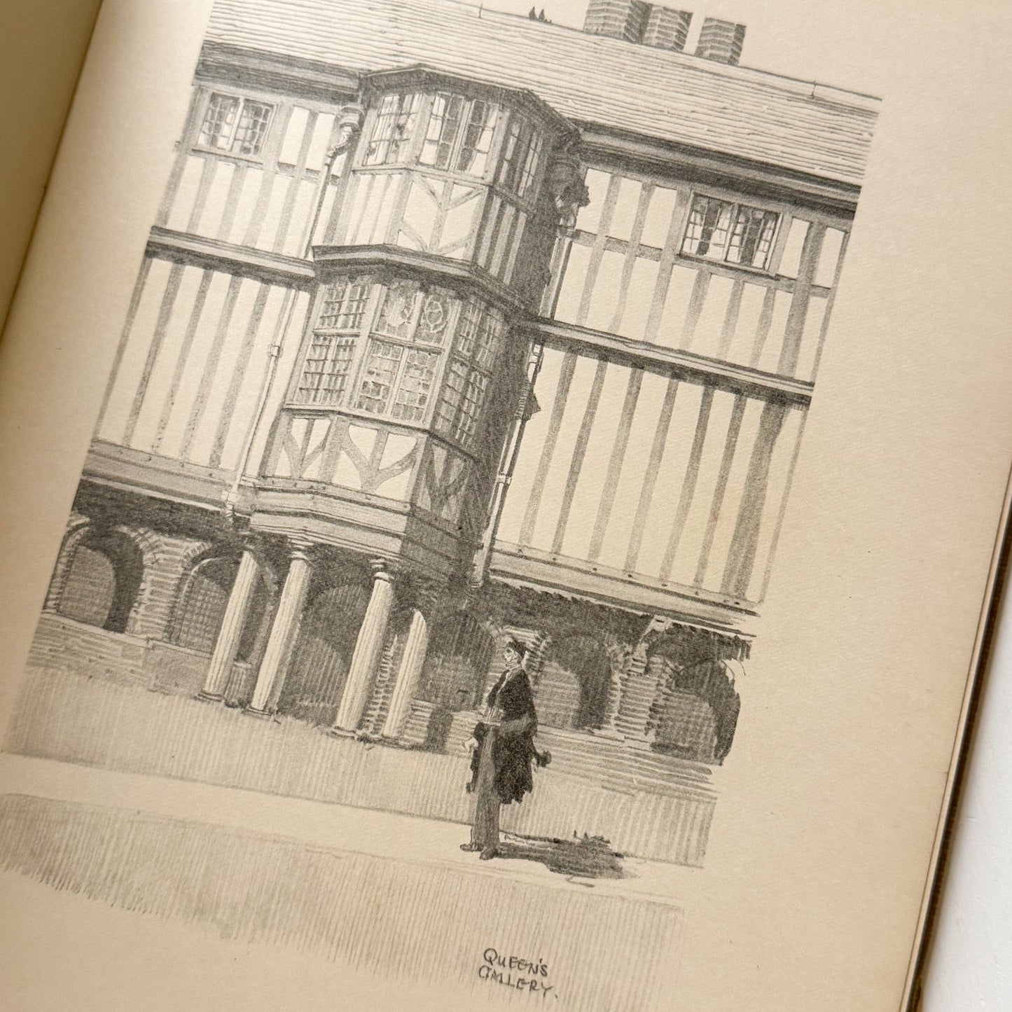 Vintage illustration of a man standing in front of a half-timbered building on an open book.